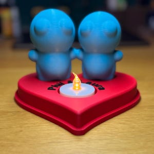 Personalised 3D printed tealight holder featuring cute bubble people figurines on a heart-shaped base. Customisable with names, perfect as a romantic Valentine’s gift, anniversary present, or home decor. Designed for use with LED tealights.