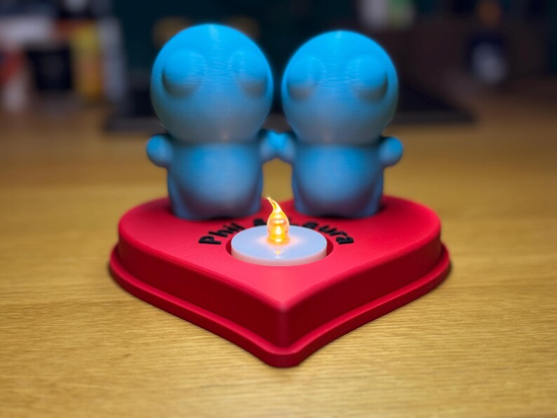 Personalised 3D printed tealight holder featuring cute bubble people figurines on a heart-shaped base. Customisable with names, perfect as a romantic Valentine’s gift, anniversary present, or home decor. Designed for use with LED tealights.