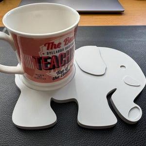 Elephant coaster holding a large mug, demonstrating the 90mm hole size and functionality as a decorative coaster.