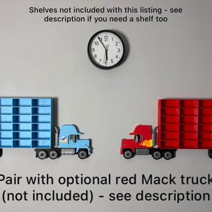 May include: Two toy semi-trucks, one blue and one red, each with a shelf-like trailer. A black clock hangs above them. The text reads "Pair with optional red Mack truck (not included) - see description."