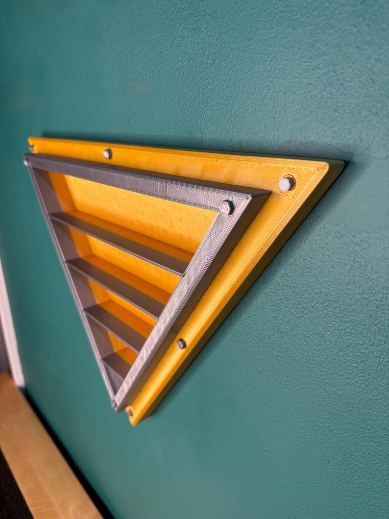 May include: A yellow and gray triangular wall shelf with multiple horizontal shelves. The shelf is mounted on a teal wall with silver colored screws. The shelf is a modern design.