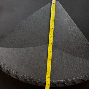 May include: A stack of black, triangular-shaped foam pieces. A yellow measuring tape shows the height of the stack is approximately 11 inches. The foam has a textured surface and appears to be new.