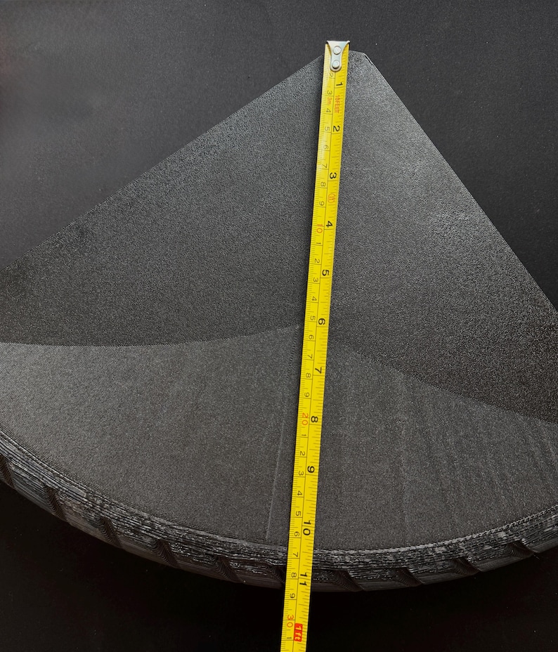 May include: A stack of black, triangular-shaped foam pieces. A yellow measuring tape shows the height of the stack is approximately 11 inches. The foam has a textured surface and appears to be new.