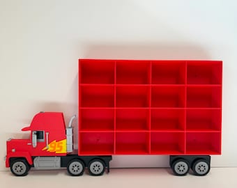 May include: A red toy truck with a cab featuring a yellow lightning bolt graphic and the number 95. The trailer is a rectangular red storage unit with sixteen open compartments arranged in a four-by-four grid, supported by black wheels.