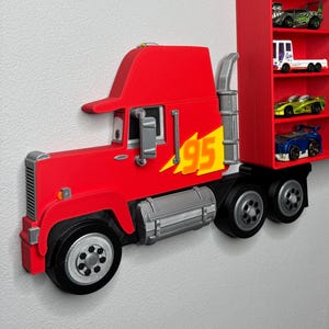 May include: A red toy truck with a trailer, featuring the number "95" and a yellow lightning bolt graphic. The trailer has multiple shelves holding toy cars. The truck is mounted on a wall.