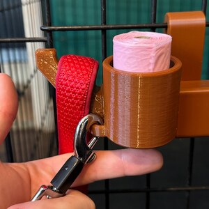 Close-up of brown PETG dog crate organiser showing the convenient slot for clipping leads. Features space for a poo bag roll and adjustable hooks for crate attachment. Heat-resistant and tool-free design, ideal for dog walkers and pet owners.