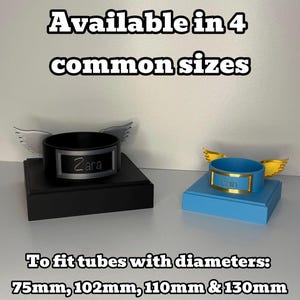May include: Two circular tube holders with attached wings, one black with silver wings and the name Zara, the other blue with gold wings and a nameplate. Text reads: Available in 4 common sizes. To fit tubes with diameters: 75mm, 102mm, 110mm & 130mm.