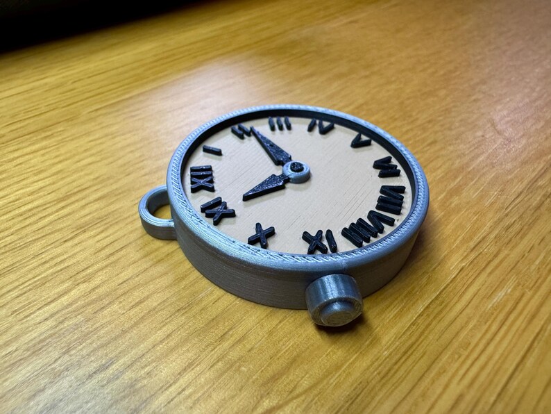 May include: A silver-coloured pocket watch with Roman numeral markings on the face. The watch has a black hour hand and a black minute hand. The watch is on a wooden surface.