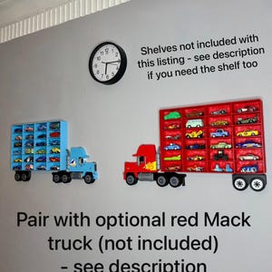 May include: Two toy truck-shaped display shelves mounted on a gray wall. One is blue, the other red, each holding miniature toy cars. A black clock hangs above the shelves. Text on the wall reads, "Shelves not included..." and "Pair with optional red Mack truck..."