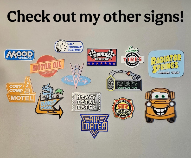 May include: A collection of colorful, die-cut signs featuring various designs and text, including "Mood Springs," "Motor Oil," "Cozy Cone Motel," and "Radiator Springs Racing Team." The signs are in various shapes and sizes.