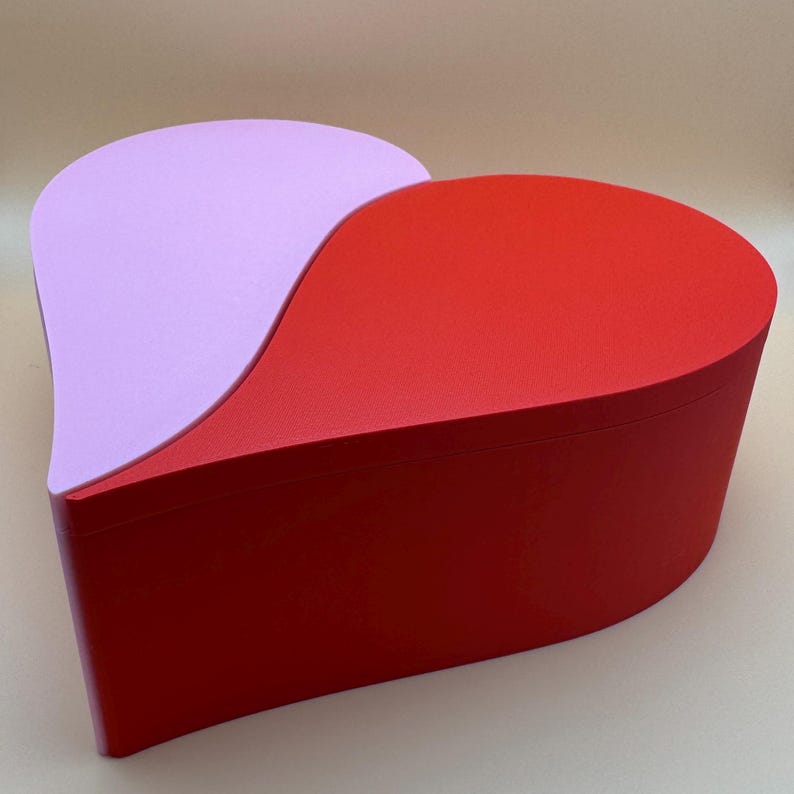 A large 3D-printed heart-shaped box in vibrant red and pastel purple with a sleek split design. Perfect for storing keepsakes, gifts, or jewellery, this eco-friendly PLA box is both functional and decorative, making it ideal for Valentine’s Day.