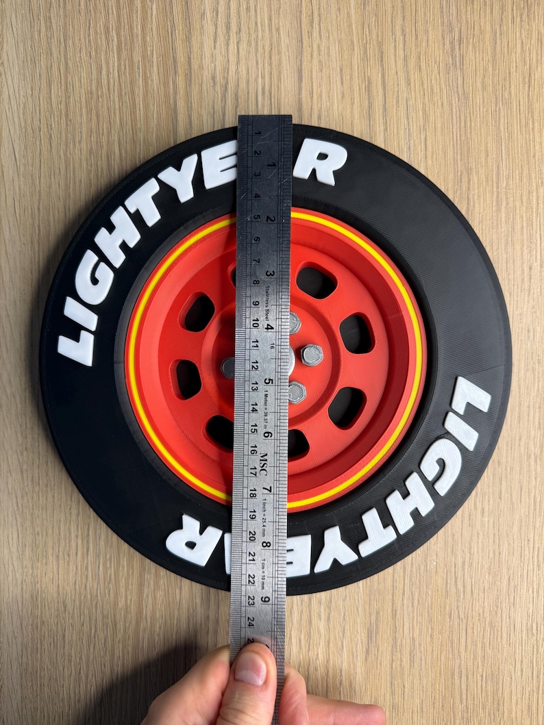 May include: A black and red decorative wheel with the text "LIGHTYEAR" in white. The wheel is approximately 9 inches in diameter, with a yellow stripe between the red center and black tire.