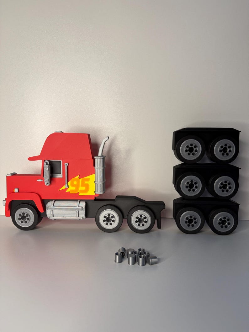 May include: A red toy truck with the number 95 and a yellow lightning bolt graphic on the side. The truck has a black chassis and silver wheels. There are three sets of black wheels and silver cylinders.