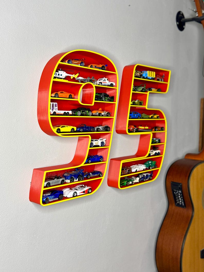 May include: Red and yellow wall-mounted display shelves shaped like the number 95, filled with miniature toy cars. The shelves are red with yellow trim, and the cars are various colors and styles.