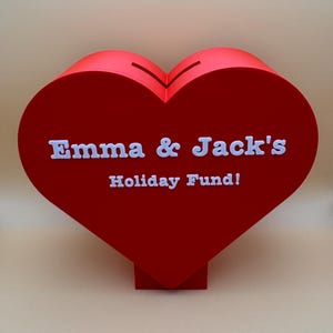 Love heart-shaped piggy bank on a stand, ideal for saving coins, Valentine’s Day gifts, or romantic decor. A unique 3D-printed coin bank for kids or couples, perfect as a gift, decorative piece, or practical savings tool.