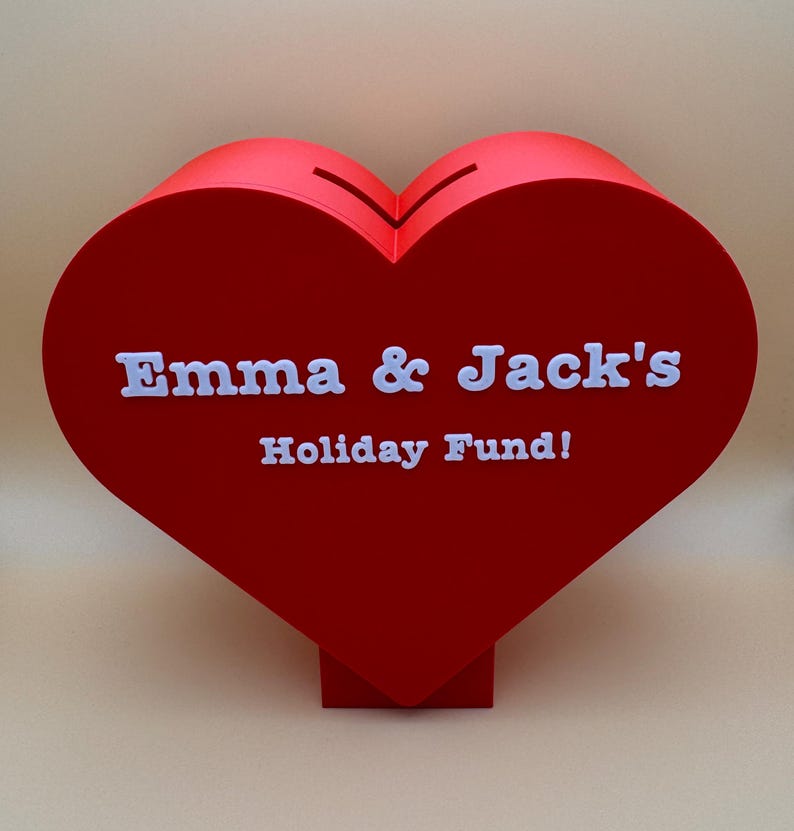 Love heart-shaped piggy bank on a stand, ideal for saving coins, Valentine’s Day gifts, or romantic decor. A unique 3D-printed coin bank for kids or couples, perfect as a gift, decorative piece, or practical savings tool.
