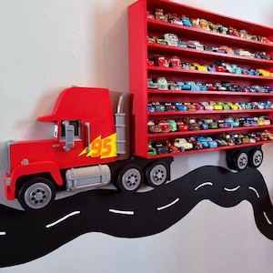 May include: A red wall-mounted display shelf shaped like a semi-truck with a trailer featuring multiple horizontal rows. The truck cab displays the number 95 in yellow. The trailer holds numerous small toy cars arranged on several shelves.