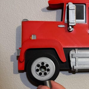 Close-up of Mack truck toy shelf showing a screw cap cover for seamless wall mounting. Practical and stylish, it hides screws for a polished look. Perfect for displaying Hot Wheels or Matchbox cars. Available in red, black, blue, or white.