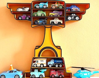 May include: A yellow and orange wall-mounted shelf unit displaying a collection of toy cars and trucks. The shelf has multiple compartments and a decorative design. The toy vehicles are in various colors and styles, including race cars, trucks, and a helicopter.
