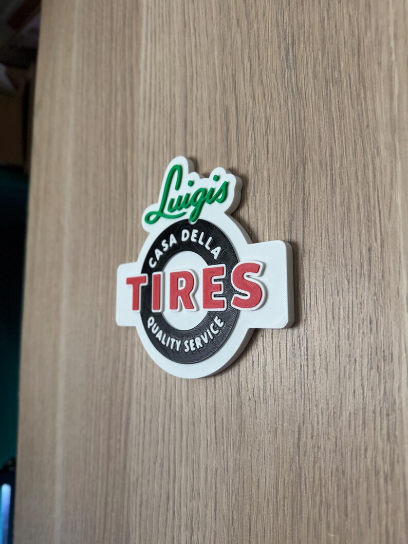 May include: A white, red, and black sign with the text "Luigi's Casa Della Tires Quality Service". The sign has a green, stylized "Luigi's" logo above the circular text.
