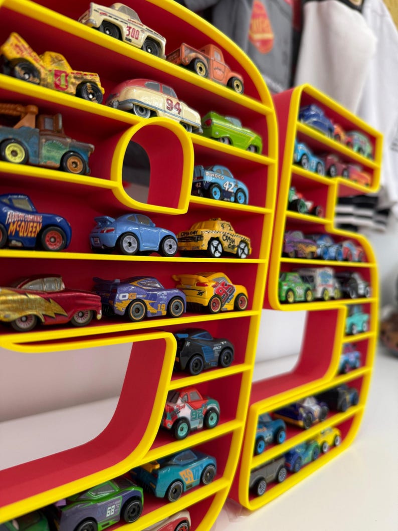 May include: A red and yellow display shelf shaped like the number 97, filled with toy cars of various colors and designs. The shelf has multiple levels to hold the toy cars. The cars are miniature replicas of different car models.