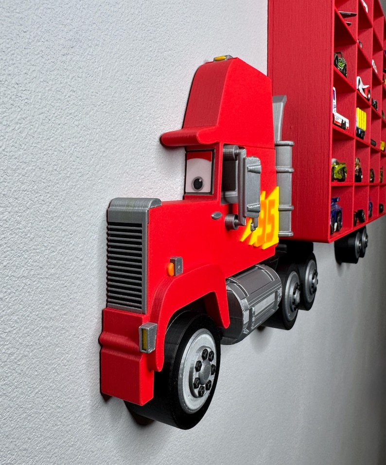 May include: A vibrant red toy truck with a matching trailer, mounted on a wall. The truck features a detailed design with gray accents, including the wheels and engine components. The trailer has multiple compartments, likely for displaying small toy cars.
