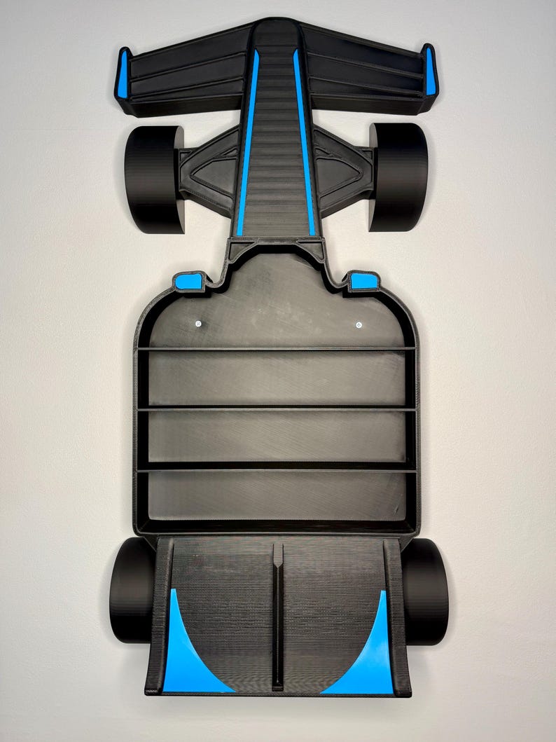 Op de afbeelding: Een zwart en blauw Formule 1 raceauto schap. Het schap heeft een zwarte carrosserie met blauwe accenten op de voor- en achtervleugels en langs het midden. Het schap heeft drie horizontale planken voor display en zwarte wielen.