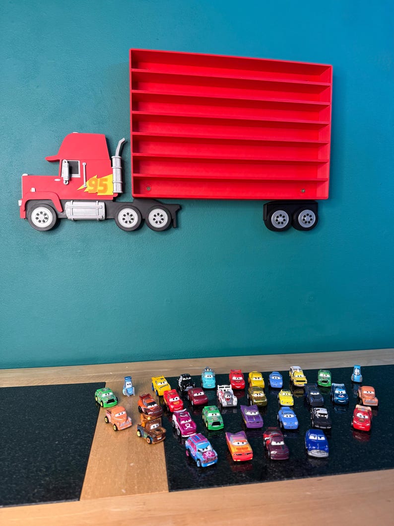 May include: A red wall-mounted display shelf shaped like a semi-truck with a trailer featuring multiple horizontal slots for small toy cars. The truck cab has a yellow lightning bolt graphic and the number 95. Numerous small toy cars are arranged below.