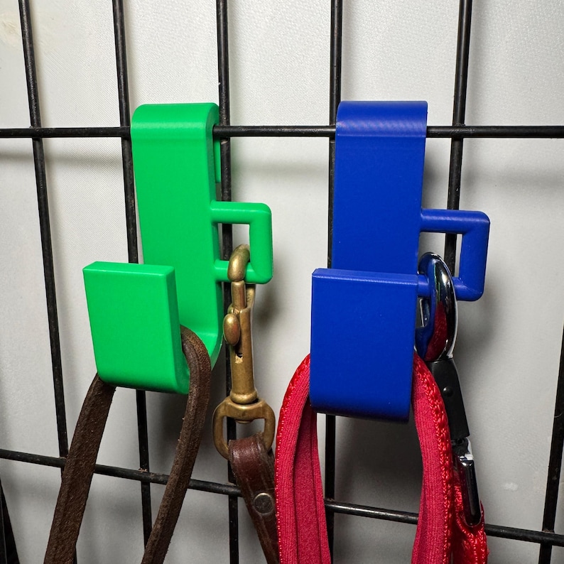Green and blue hooks designed for dog crates securely hold leads and feature a clip for lead clasps. Easy to attach, no screws or installation needed. Perfect for home or car use. Heat-resistant and durable.