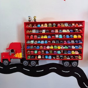 May include: A red wall-mounted display shelf shaped like a semi-truck trailer, featuring multiple horizontal rows filled with small die-cast toy cars. The truck cab is red with a yellow number 95 decal on the side and grey wheels.