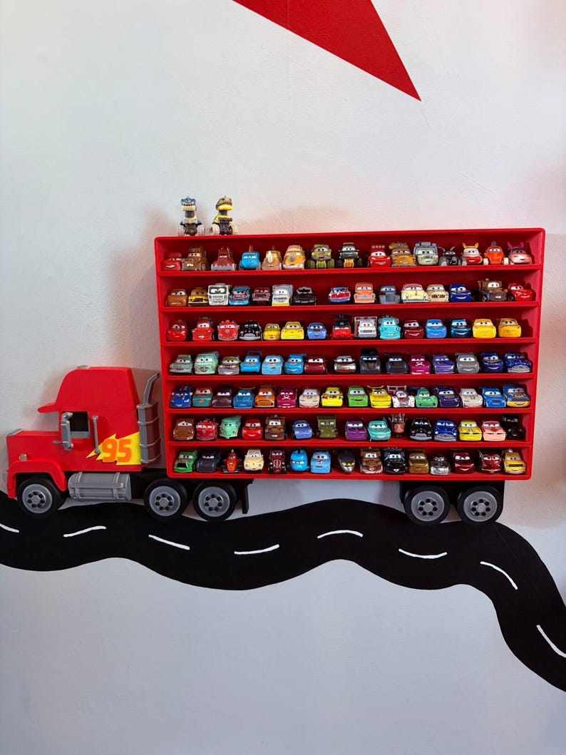 May include: A red wall-mounted display shelf shaped like a semi-truck trailer, featuring multiple horizontal rows filled with small die-cast toy cars. The truck cab is red with a yellow number 95 decal on the side and grey wheels.