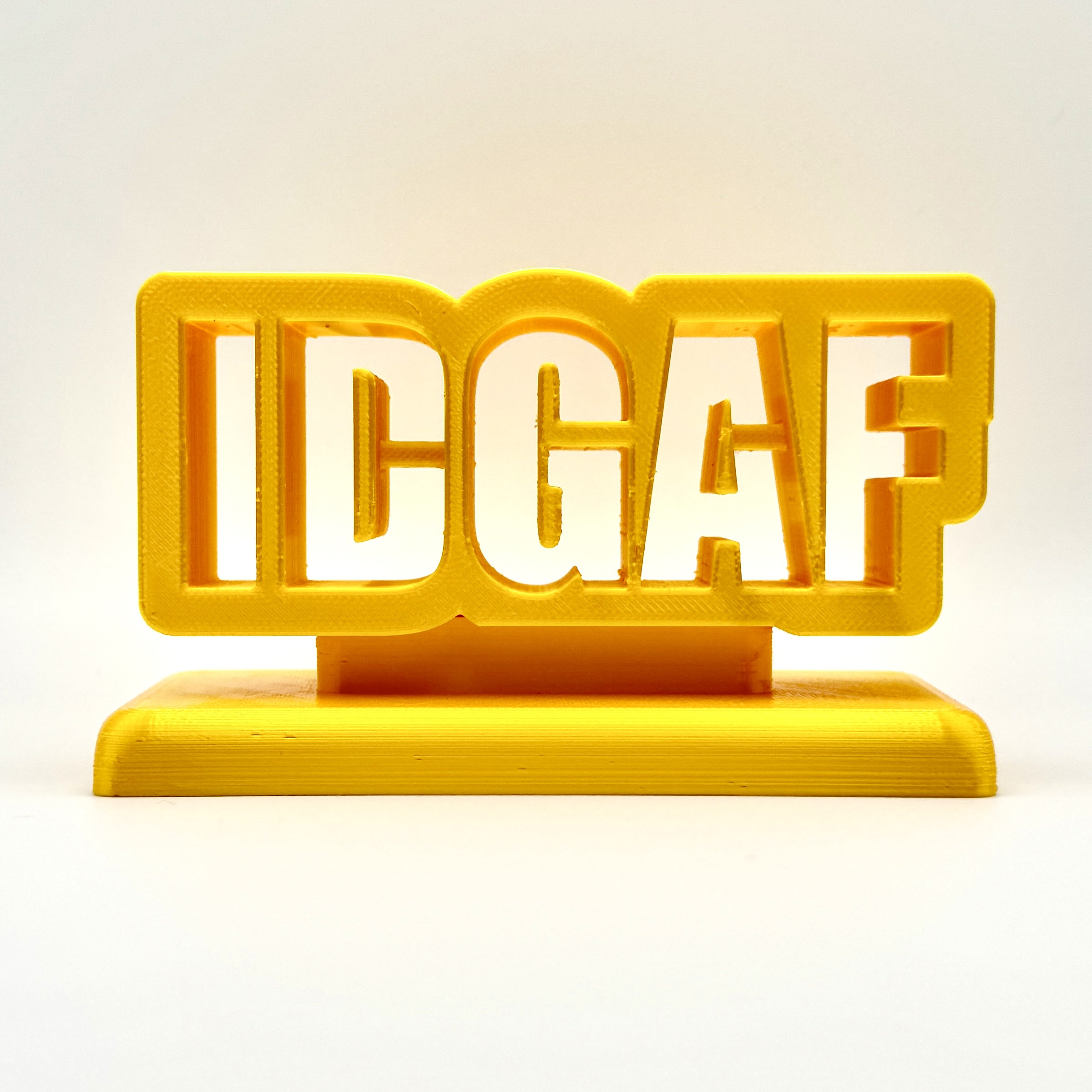 Bright yellow 3D printed 'IDGAF' sign, perfect for desk, shelf, or trophy display, showcasing bold and playful lettering.
