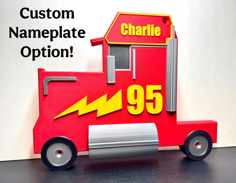 A 3D-printed red truck display inspired by Mack from Cars, featuring a bold yellow “95” and a lightning bolt. Silver details add realism, and a custom nameplate option is shown, reading “Charlie.”
