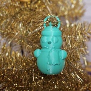 3D-printed snowman ornament made from PLA, available in vibrant colours with a built-in loop for hanging. Perfect for decorating Christmas trees, wreaths, or as festive gifts. Lightweight and durable, adding a handmade charm to holiday décor.