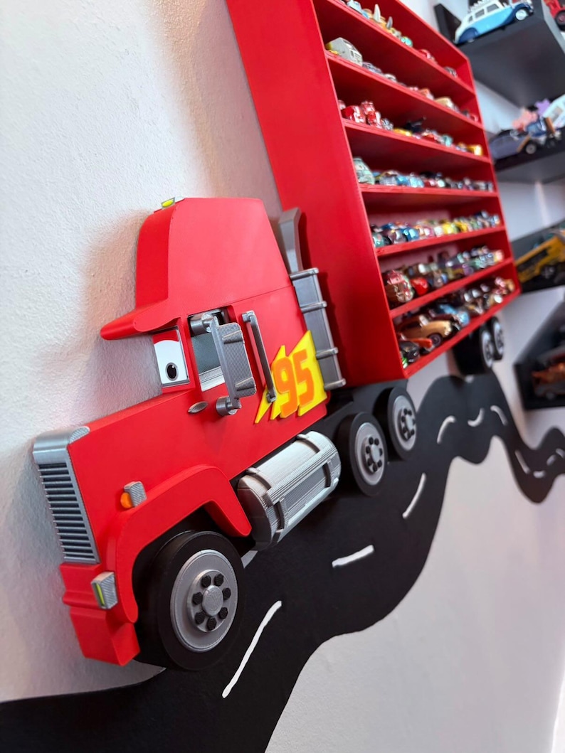 May include: A red wall-mounted display shelf shaped like a semi-truck with a trailer featuring multiple horizontal tiers for toy cars. The truck cab displays a yellow lightning bolt emblem with the number 95, and it is positioned on a black road decal.