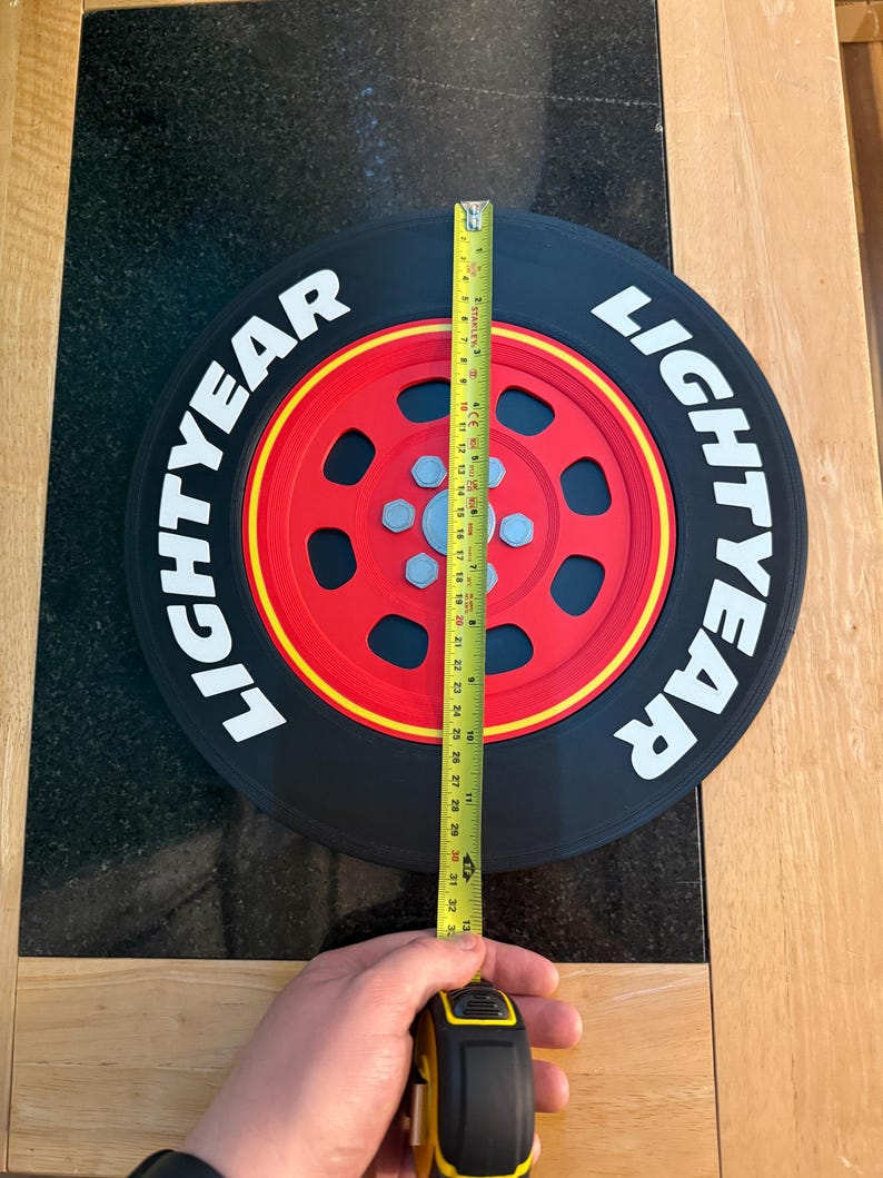 May include: A black and red Lightyear tire with the word "LIGHTYEAR" in white. The tire is being measured with a yellow tape measure, showing a diameter of approximately 32 inches.