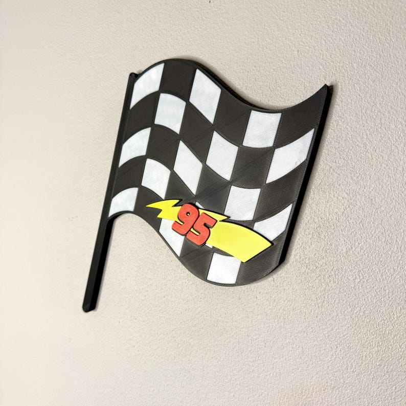 May include: A black and white checkered flag with a black pole. The flag has a yellow lightning bolt with the number 95 in red. The flag is a decorative item.