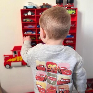 Child playing with a wall-mounted display inspired by Disney’s Mack from Cars, perfect for kids to showcase their car collections. The truck design adds a playful touch while providing organised storage for toy cars, making it both fun and functional