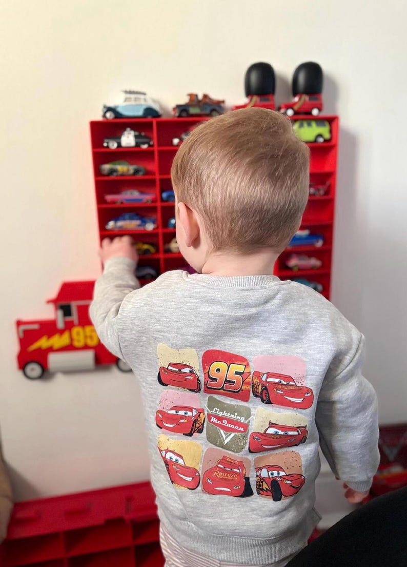 Child playing with a wall-mounted display inspired by Disney’s Mack from Cars, perfect for kids to showcase their car collections. The truck design adds a playful touch while providing organised storage for toy cars, making it both fun and functional