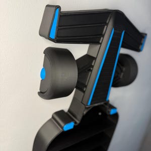 Op de afbeelding: Een zwart en blauw decoratief object, mogelijk een auto-onderdeel, gemonteerd op een witte muur. Het object heeft een complex, geometrisch ontwerp met blauwe accenten en een reeks horizontale lijnen. Het object lijkt 3D-geprint te zijn.
