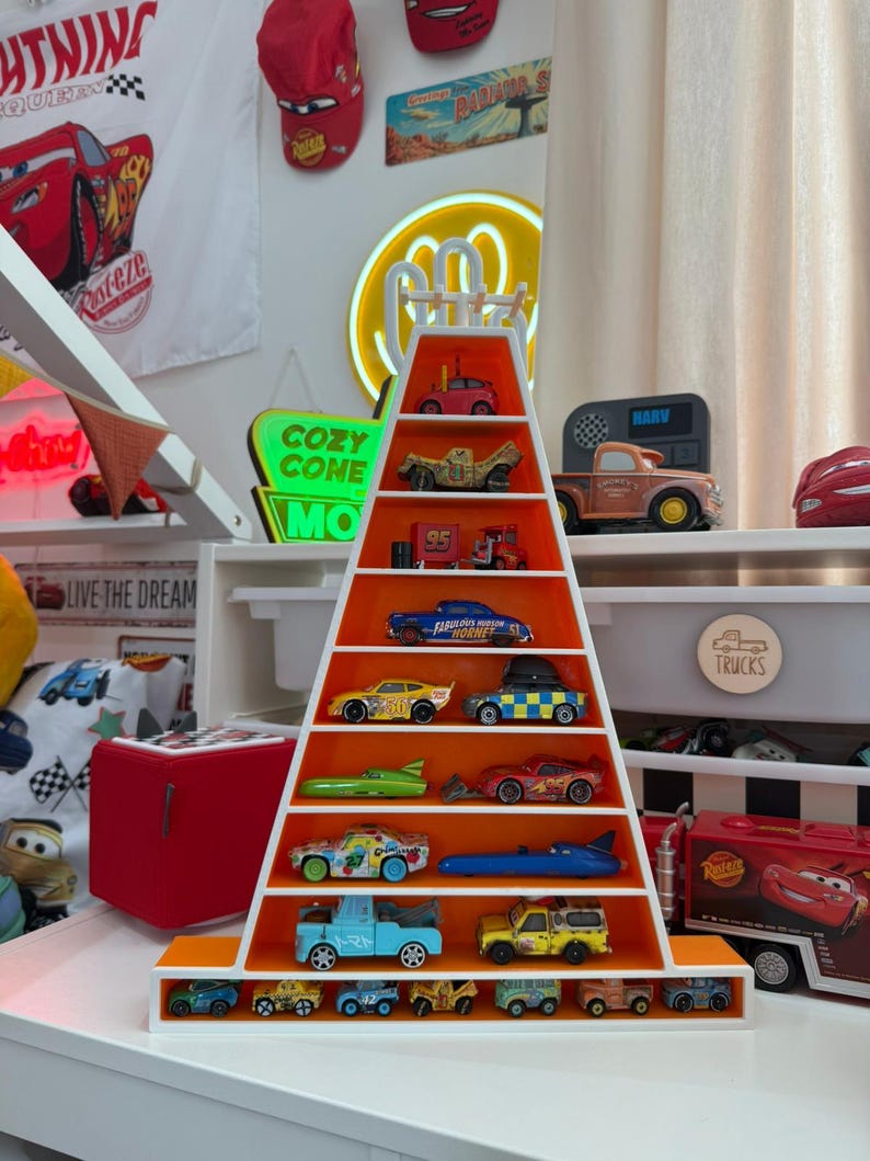 May include: A white and orange pyramid-shaped shelf unit displaying a collection of toy cars. The cars are various colours and designs, including a blue race car and a yellow truck. The shelf is decorated with a Cars theme.