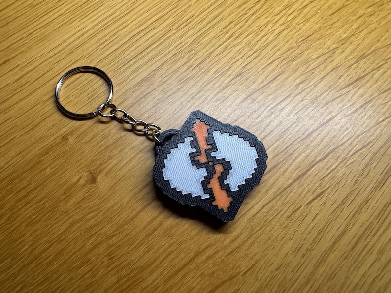 A closeup image of a 3D printed keyring, the key ring is an intentionally pixelated version of the Runecrafting skill icon from Old School Runescape OSRS. It is around 6mm thick and 40x40mm