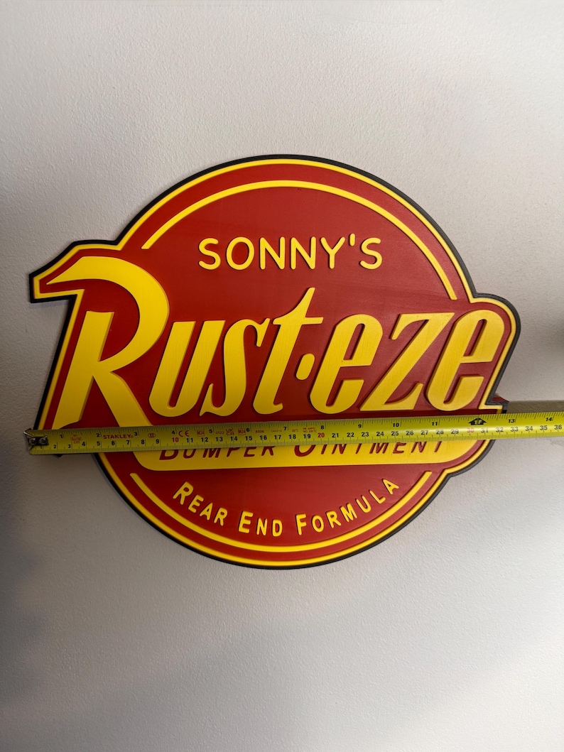 Puede incluir: Un letrero de madera rojo y amarillo con el texto "SONNY'S Rust-eze BUMPER OINTMENT REAR END FORMULA". El letrero mide aproximadamente 61 cm de ancho.