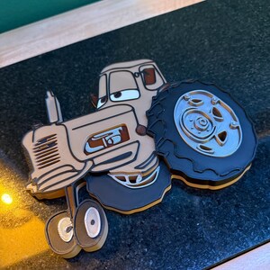 以下が含まれることがあります： ベージュ、茶色、黒色の3Dプリントトラクター。トラクターは大きなタイヤ、詳細なエンジン、笑顔の顔をしています。デザインはレイヤーになっており、立体的な外観になっています。トラクターはおもちゃまたは装飾品です。