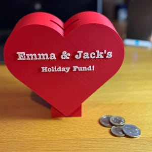 Coins for scale next to a Love heart-shaped piggy bank, ideal for saving coins, Valentine’s Day gifts, or romantic decor. A unique 3D-printed coin bank for kids or couples, perfect as a gift, decorative piece, or practical savings tool.