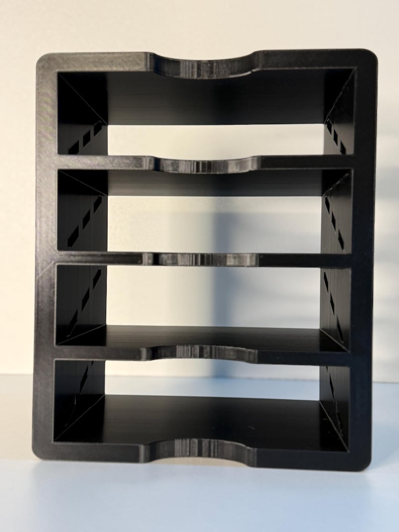 May include: A black, four-tiered organizer with a rectangular frame. Each shelf has a curved cutout in the front. The sides feature diagonal support beams. The organizer is made of a solid, matte black material.