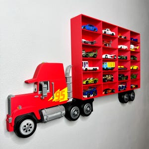 May include: A red semi-truck shaped wall shelf with multiple compartments, filled with toy cars. The truck features the number 95 in yellow and a cartoon-like design. The shelf is mounted on a white wall.