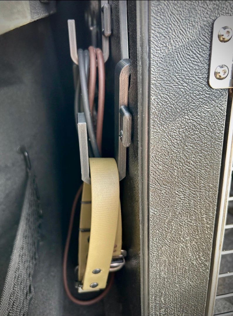 A 3D-printed organiser securely mounted inside a dog crate, designed to hold leads and accessories neatly. A beige leather collar and multiple leads are stored within the hooks, keeping them tangle-free.