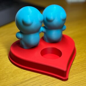 Personalised 3D printed tealight holder featuring cute bubble people figurines on a heart-shaped base. Customisable with names, perfect as a romantic Valentine’s gift, anniversary present, or home decor. Designed for use with LED tealights.