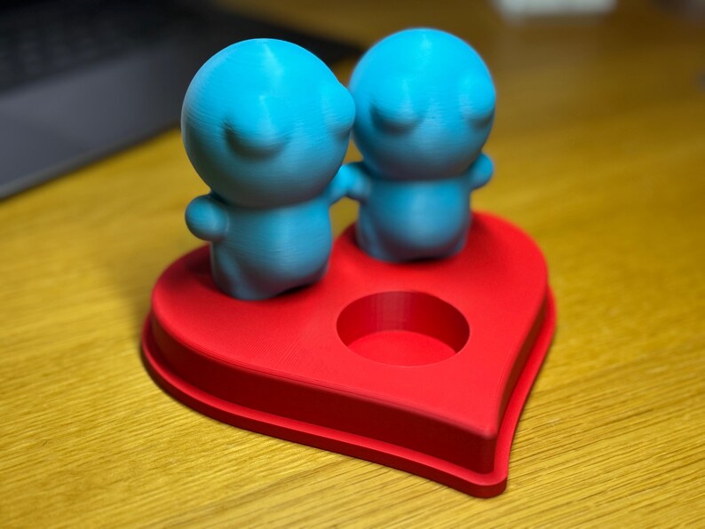 Personalised 3D printed tealight holder featuring cute bubble people figurines on a heart-shaped base. Customisable with names, perfect as a romantic Valentine’s gift, anniversary present, or home decor. Designed for use with LED tealights.